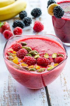 Raspberry and blackberry smoothies garnished with fresh fruit and pistachio nuts. Healthy breakfast idea.