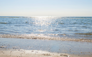 Beach along the North Sea below a blue sky in sunlight in summer