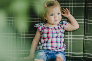Fototapeta premium The small child sits on the sofa in room
