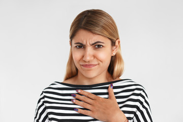 Portrait of unhappy frowning young woman grimacing and keeping hand on her chest, disgusted with unpleasant gross smell, holding breath. Negative human facial expression and bad smelling concept