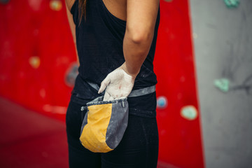 Rear view of unrecognizable female applying magnesium chalk powder on hands from a bag tied to her...