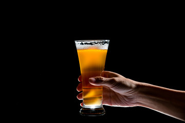 Hand holding glass of craft beer on black background