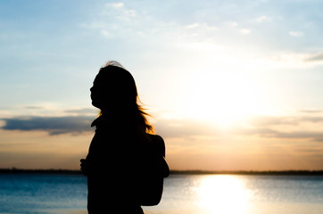 Woman silhouette standing alone in sunset scene,beautiful sky in the evening.