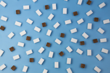 Fototapeta na wymiar Sweets pattern. Brown and white sugar cubes on blue background.