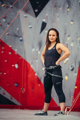 Portrait of stocky athletic woman with harness in fitness studio over artificial brightly painted rock background. Extreme sport, active lyfestyle, healthcare concept
