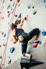 Sporty successful business woman being busy at her hobby-bouldering. Well equipped woman training...