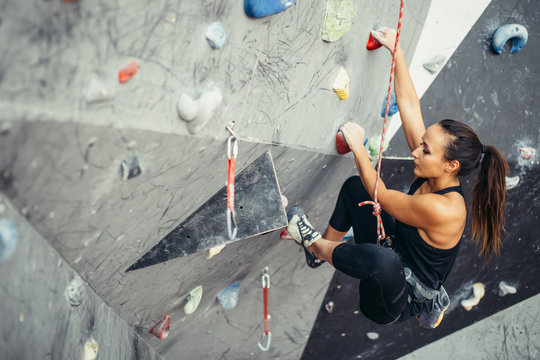 Beautiful young woman in black outfit looking at camera climbing on  practical wall in gym, bouldering, extreme sport, rock-climbing concept  Stock Photo - Alamy