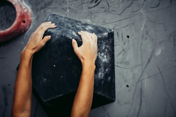 Female climber hands clenching artificial boulder in climbing gym, closeup shot - obrazy, fototapety, plakaty