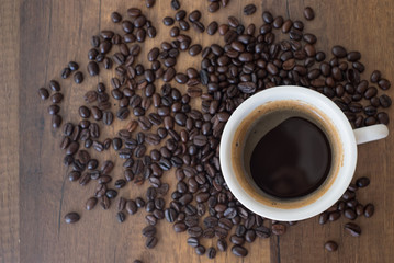 Coffee cup and coffee beans on wooden table background