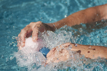 closeup of hands of man splashing with plastic rubber ducks toys in swimming pool