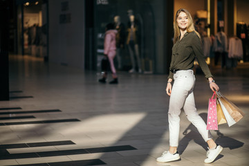 Beautiful young woman with shopping bags while standing at clothing store