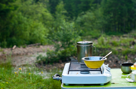 Cooking food at a campfire outdoors, hot tea in a teapot, camping camp, hiking concept