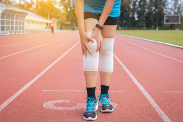 Fototapeta premium Woman runner suffering from pain in leg be injured,Hands touching her knee after jogging and workout outdoor on track running