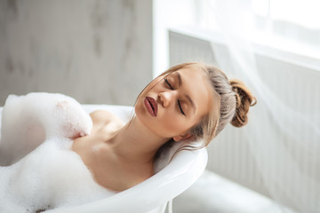 spa cure treatment.nice girl lying in the bath with closed eyes. peace concept. girl in the soft foam