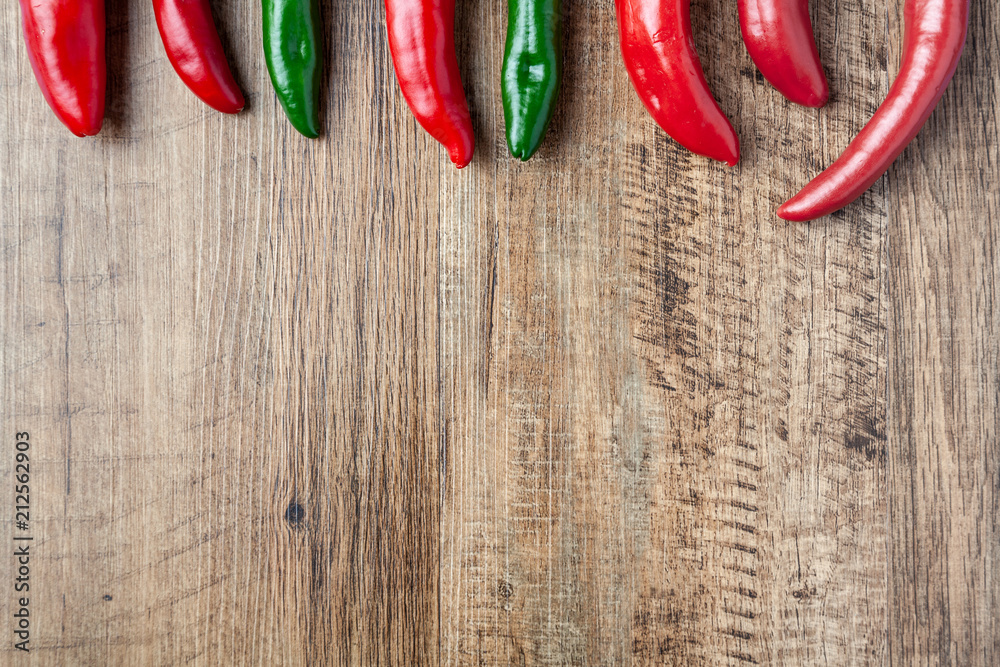 Wall mural Red and green chilli pepper on wooden table with copy space