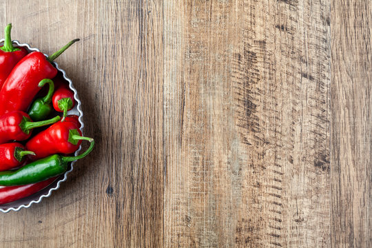 Red and green chilli pepper in a dish on wooden table with copy space