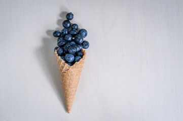 Ice cream horn or cone with blueberry on white background. Berry flat lay minimalism. Top view, place for text.