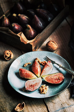 Close up of fresh fig slices served on plate with nuts on wooden table