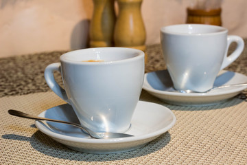 Still-life, two coffee cups, white serving plates, small metal spoons