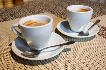 Composition, two white coffee cups, serving plates, small metal spoons