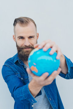 Young smiling bearded man holding globe