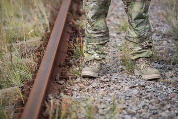 Man in army boots and uniform stands on small stones in summer.Selective focus