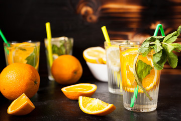 Glasses with orangeade and lemonade on dark vintage wooden background