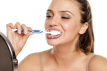 young happy woman brushing her teeth on white background