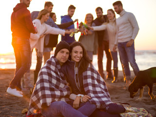Couple enjoying with friends at sunset on the beach