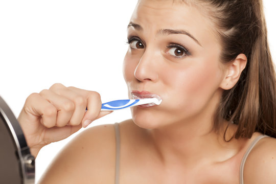 young happy woman brushing her teeth on white background