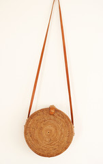 Bohemian-style Rattan Ata Bag from Bali with long leather straps, isolated on white wall