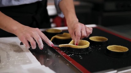 Cooking class, culinary. food and people concept. Woman's hands cutting off the extra dough with knife, biscuit dough. Studio. Slow motion