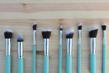Makeup brushes set on light wooden table background with copy space for text closeup top view image. Beauty visage and makeup design concept.
