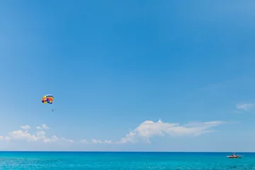 Crédence de cuisine en verre imprimé Sports nautique Personnes volant sur un parachute coloré remorqué par un bateau à moteur