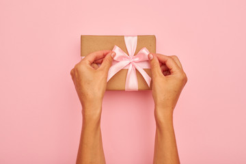 Hands tying pink bow on a present box
