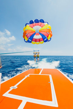 Couple of tourists flying on a multi colored parachute