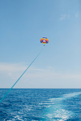 People flying on a colorful parachute towed by a motor boat