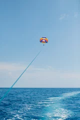 Foto op Canvas Mensen vliegen aan een kleurrijke parachute getrokken door een motorboot © meatbull