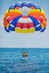 Couple of tourists flying on a colorful parachute