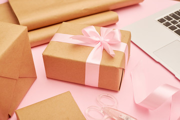 Cute present box with laptop placing on pink flatlay 