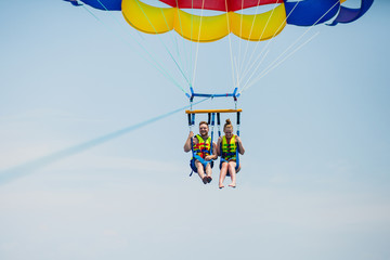 Couple of tourists flying on a colorful parachute