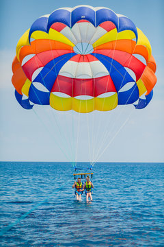 Couple of tourists flying on a colorful parachute
