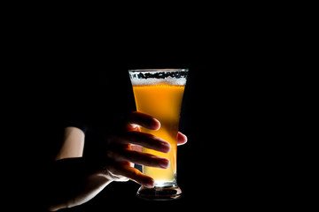 Hand holding glass of craft beer on black background