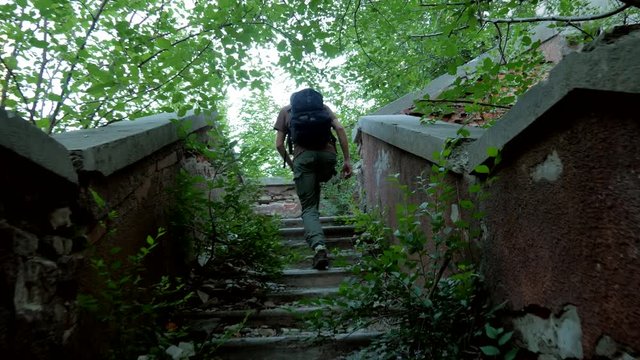 Traveler rises on old steps with a lot green trees and bushes  