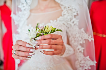 Close-up photo of bride holding her freesia boutonniere in her hands.