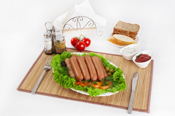 Fototapeta na wymiar Sausages smoked with tomatoes, cucumbers and greens. Served with black or white bread.