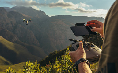 Photographe de la nature pilotant un drone dans les montagnes