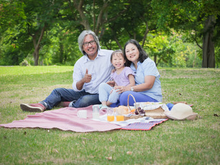 Grandparents and grandchild having a picnic in the home garden,Happy family concept.