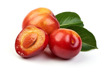 Ripe sweet red plums with leaves and a half of red plum fruit with core, isolated on white background. Close-up.