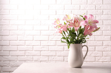 Beautiful blooming lily flowers near brick wall